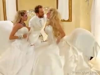 Dois blondies com enorme baloons em bridal dresses compartilhando um caralho